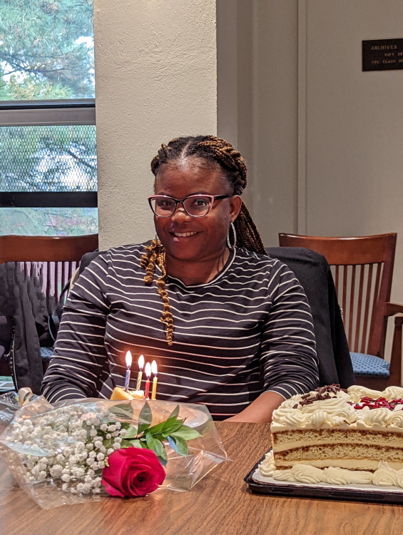 Olu simling in front of a birthday cake with lit candles.