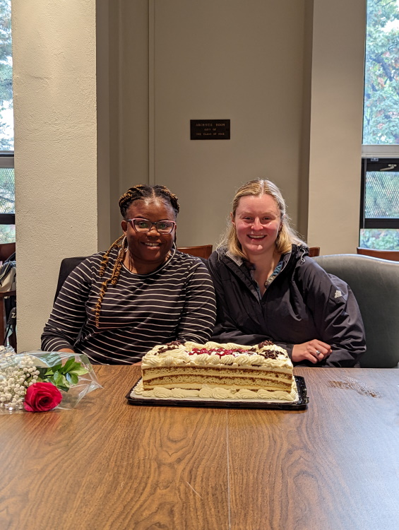 DAISY members Olu and Kathleen in front of a cake.